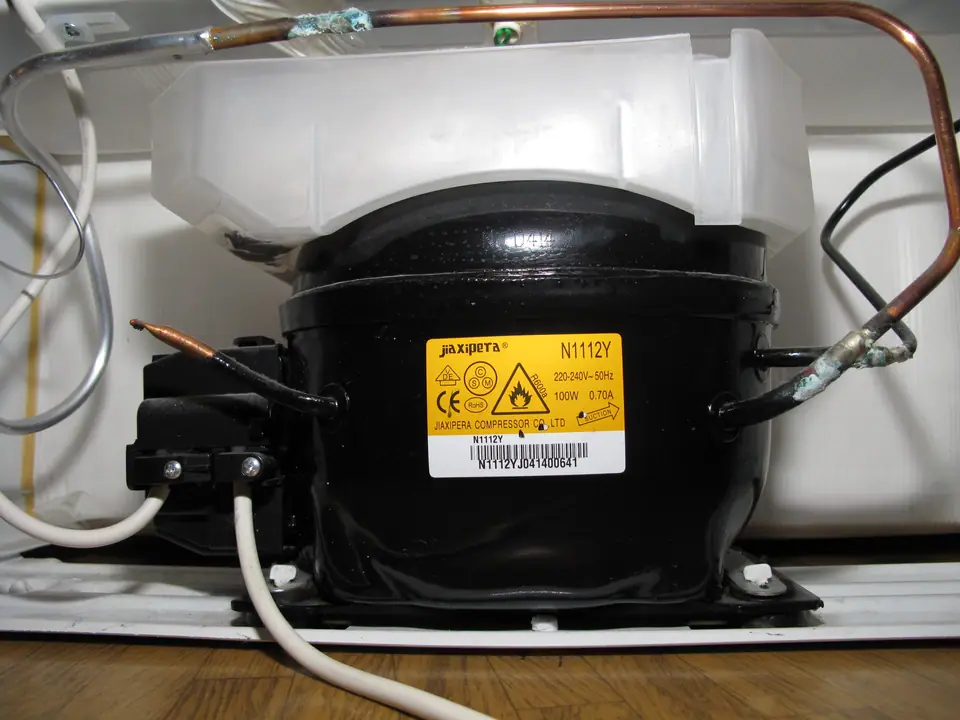 El compresor de una heladera doméstica, con los tubos de cobre que llevan el refrigerante y la bandeja de deshielo